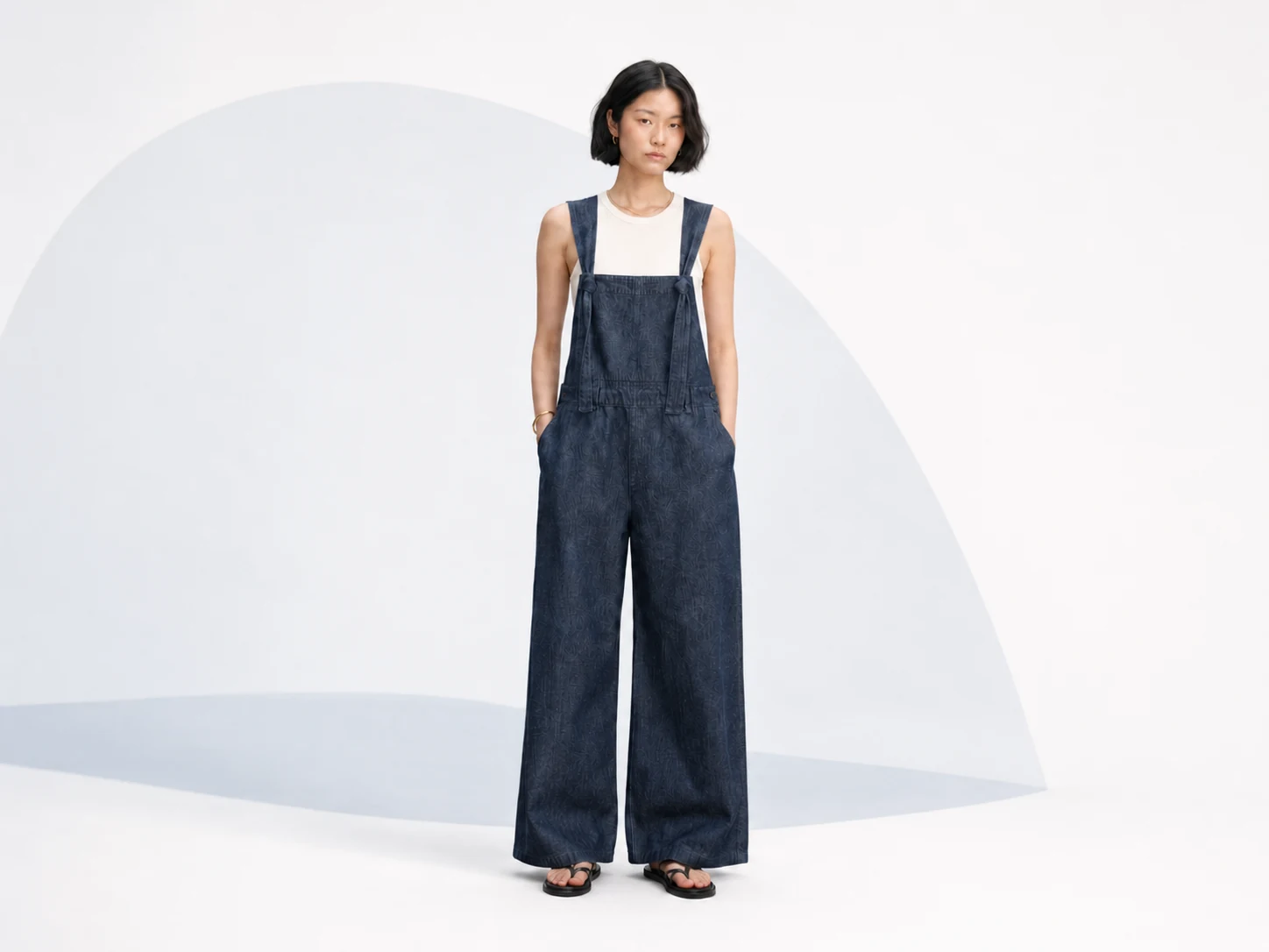Female model wearing dark indigo wide-leg custom denim overalls