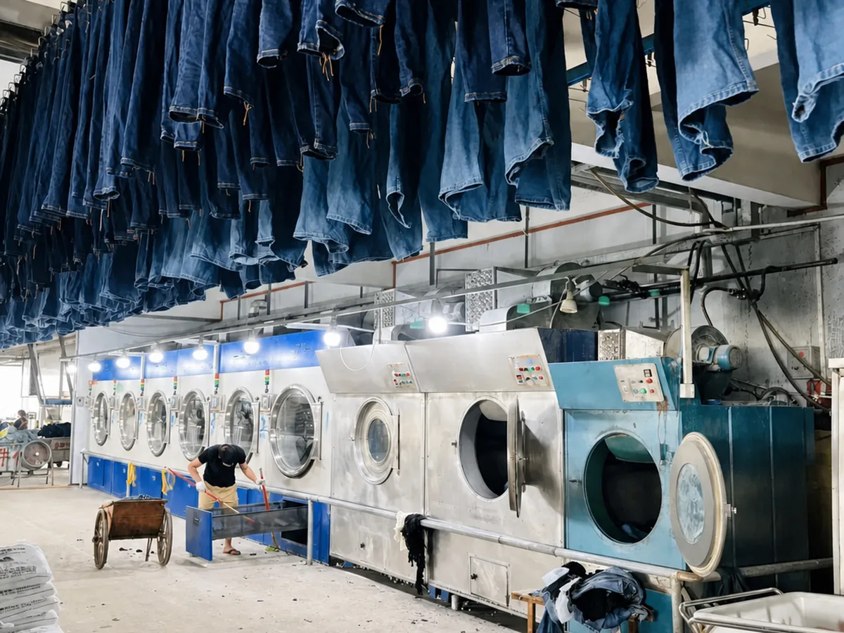 Jeans hanging above industrial denim washing and finishing machines