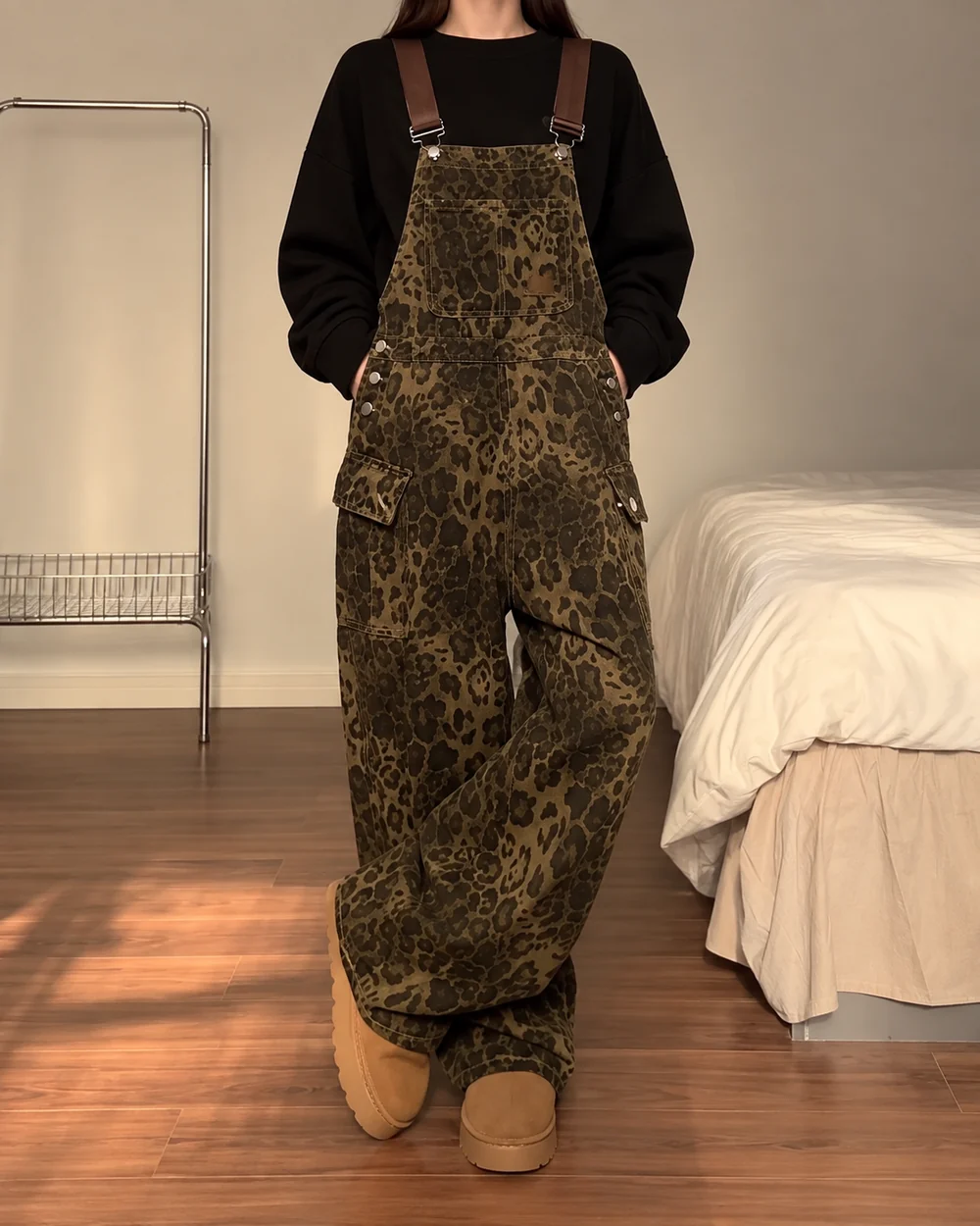 Faceless model wearing leopard-wash denim overalls with balloon legs and utility pockets