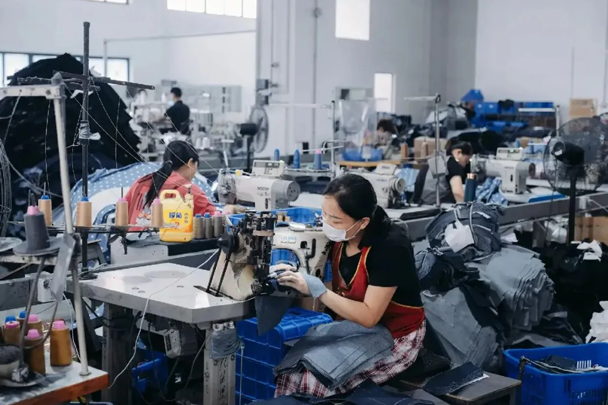 Denim factory worker sewing garments on an industrial sewing machine