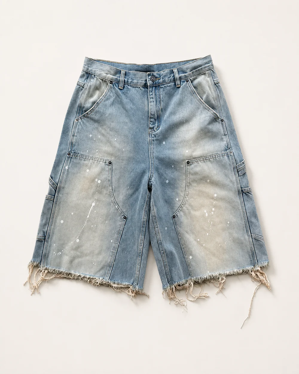 Light-wash carpenter denim jorts with paint splatter patch pockets and a raw hem