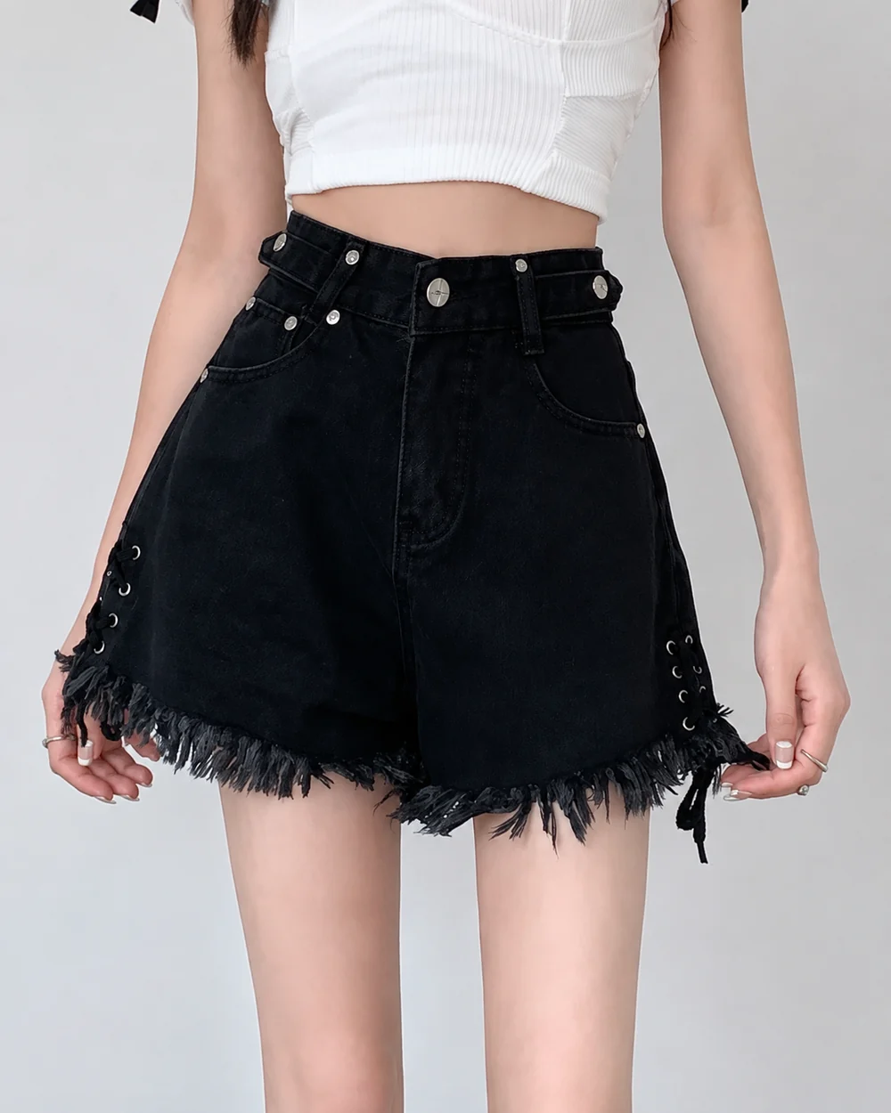 Women's black high-waisted denim shorts with lace-up sides and an asymmetric frayed hem