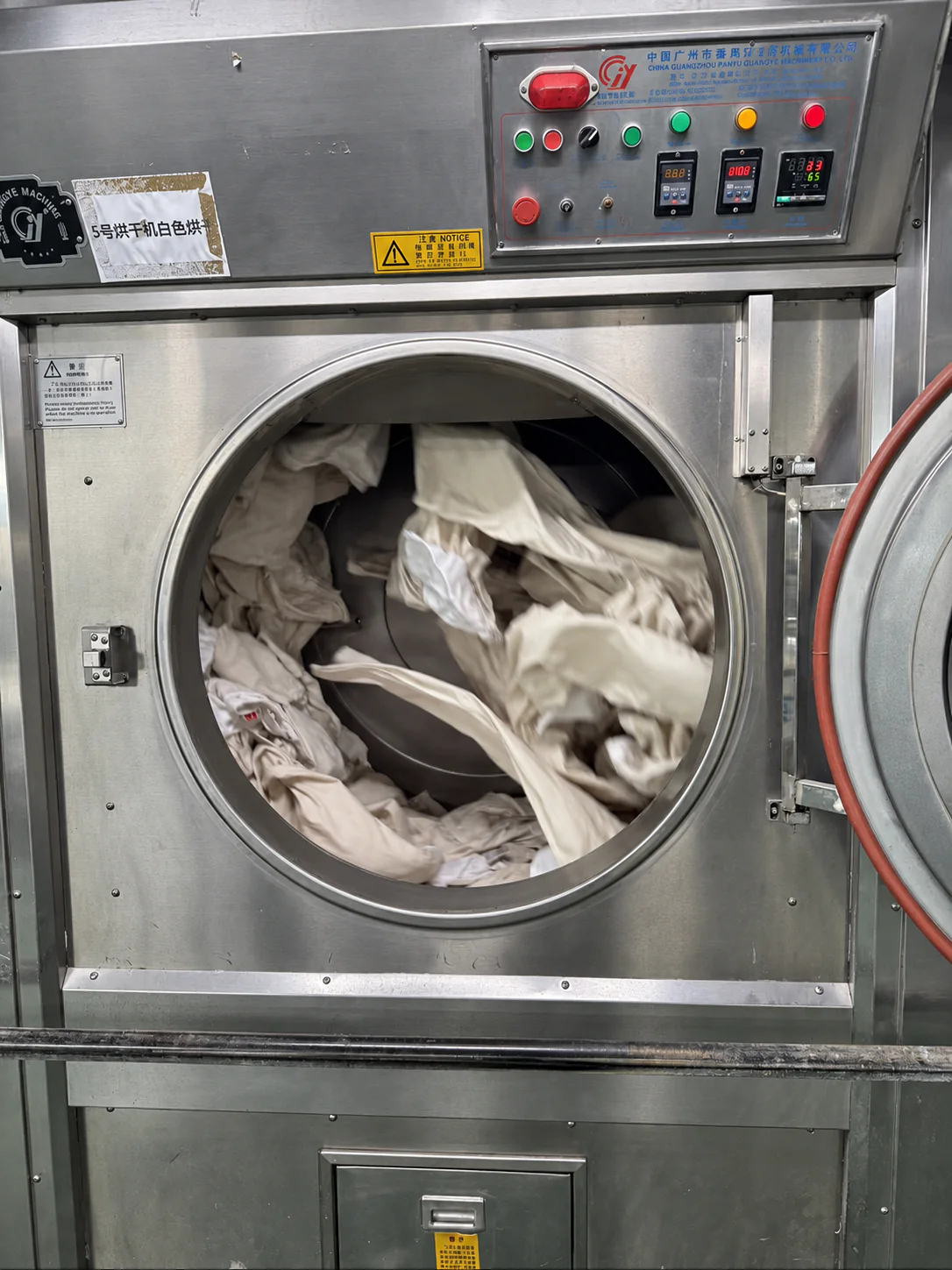 Garments tumbling inside an industrial washing machine at the denim factory