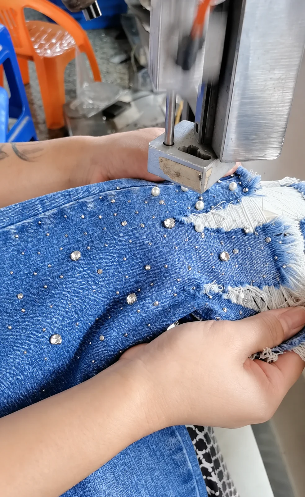 Machine applying crystal embellishments to a denim garment panel