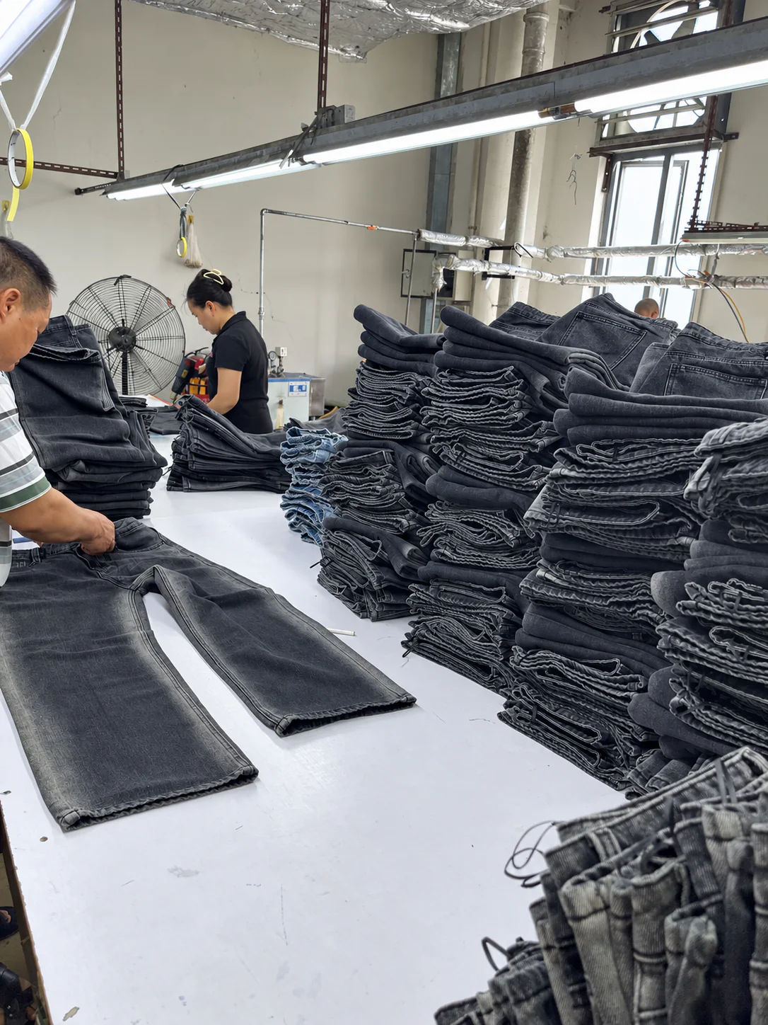 Workers checking and organizing finished washed denim jeans