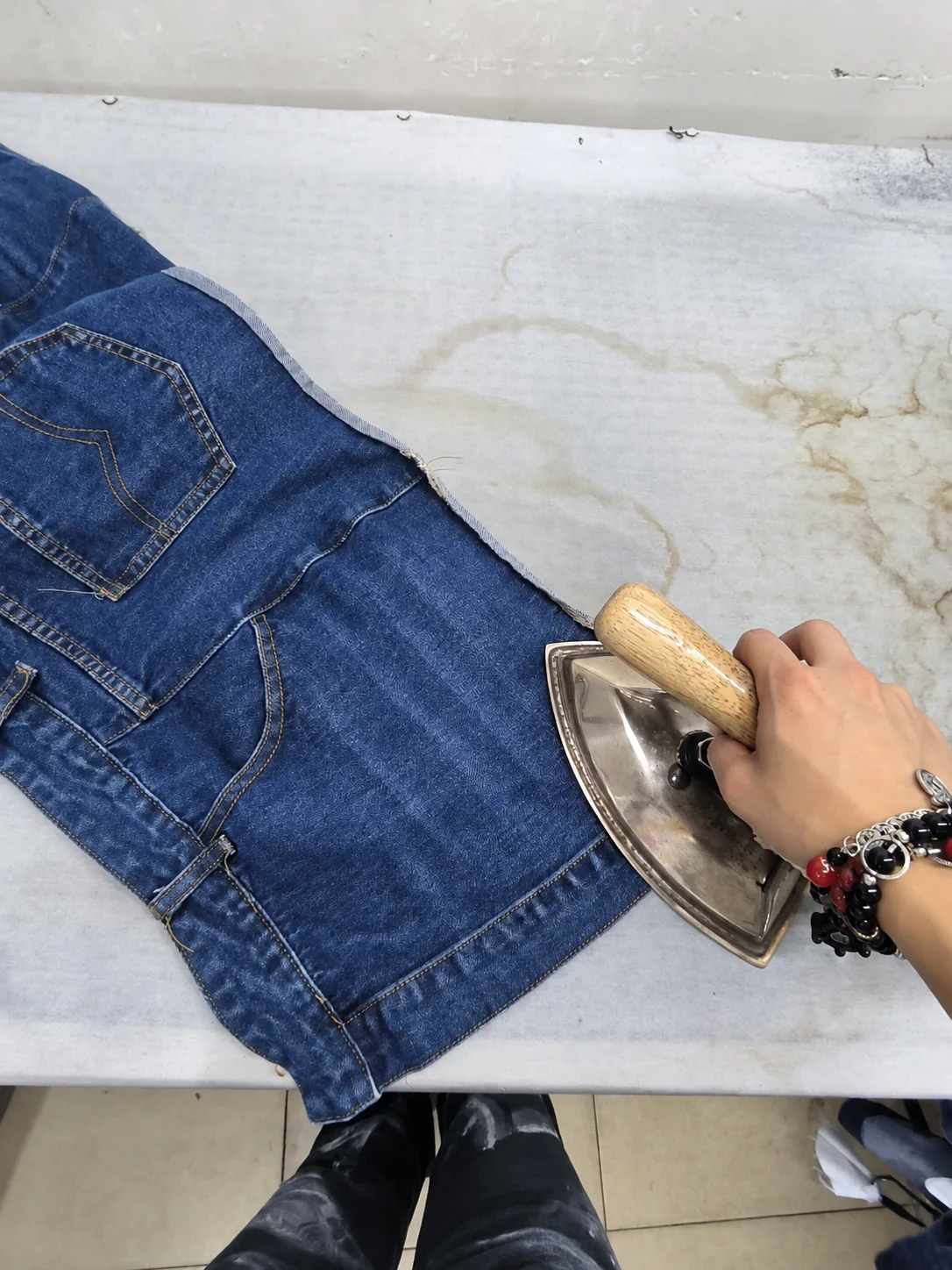 Worker pressing a denim garment during final finishing