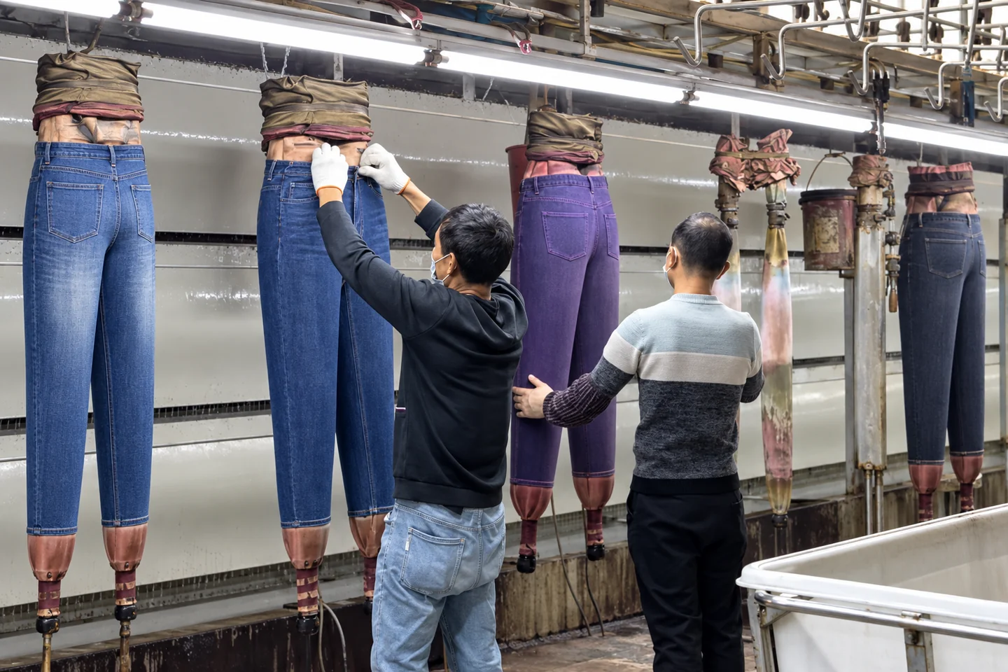 Workers applying PP spray treatment to denim jeans during garment washing at Beilin Denim