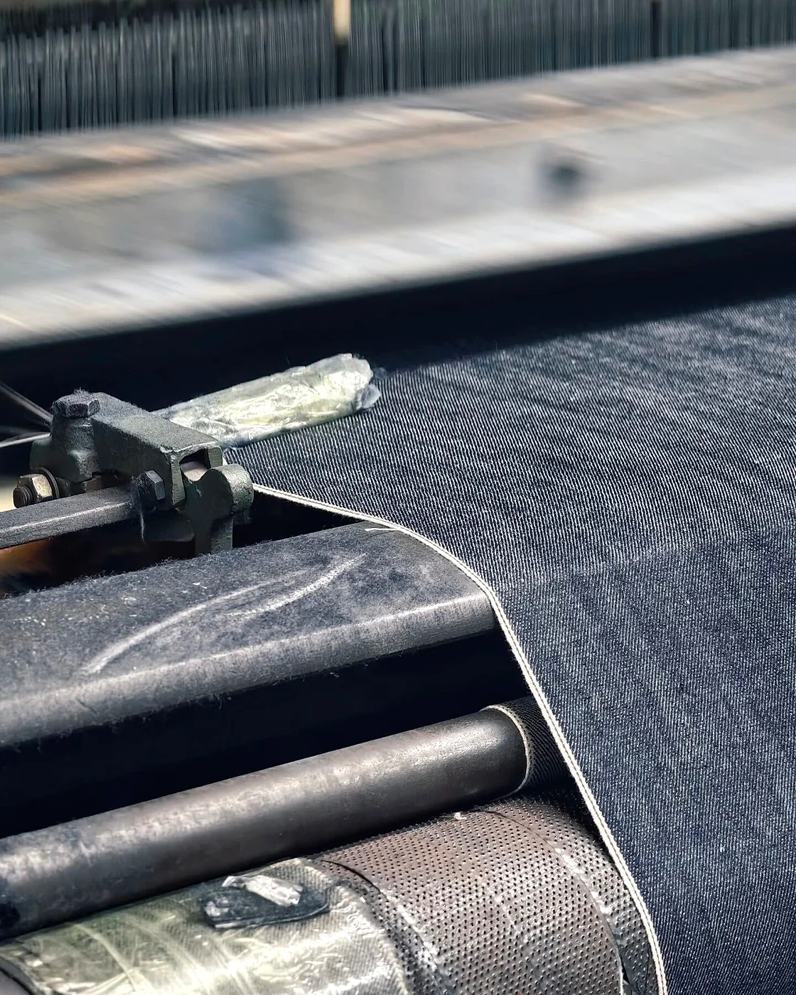 Indigo denim fabric running over rollers in industrial textile machinery