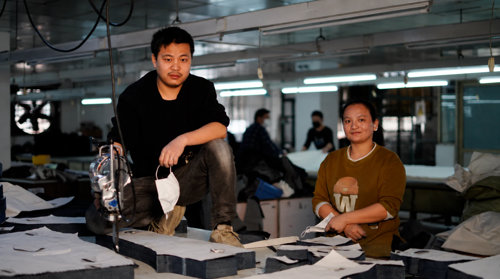 Two garment workers preparing cut components in a denim production workshop