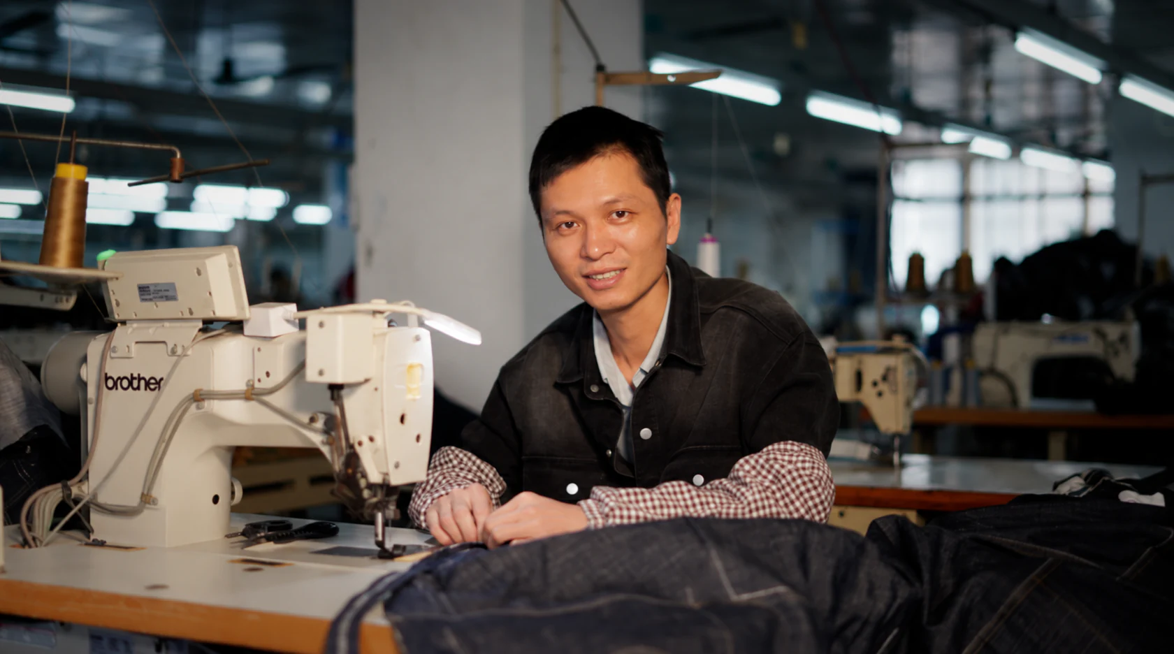 Sewing operator working on denim garments with an industrial sewing machine