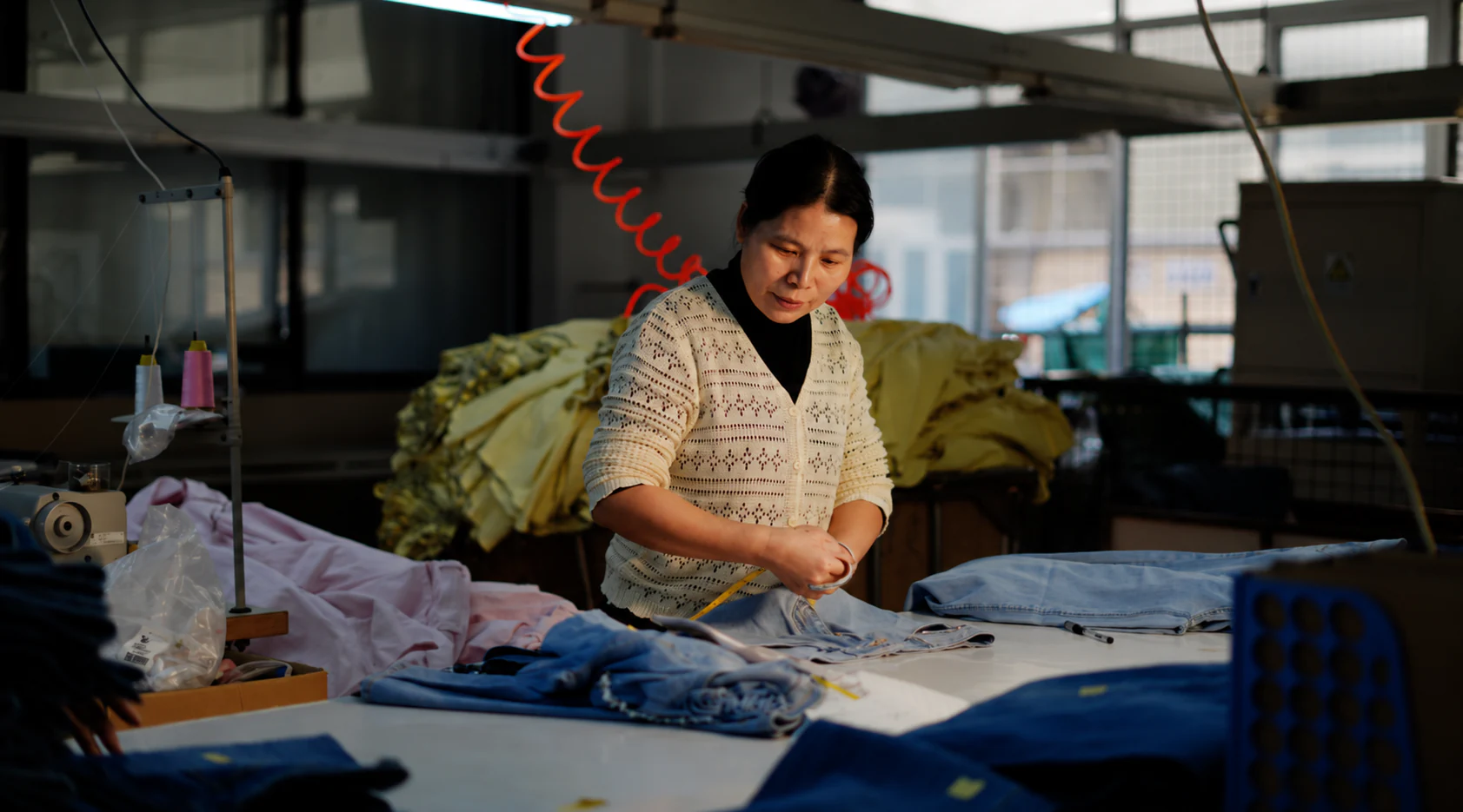 Denim production worker reviewing garment measurements on the factory floor