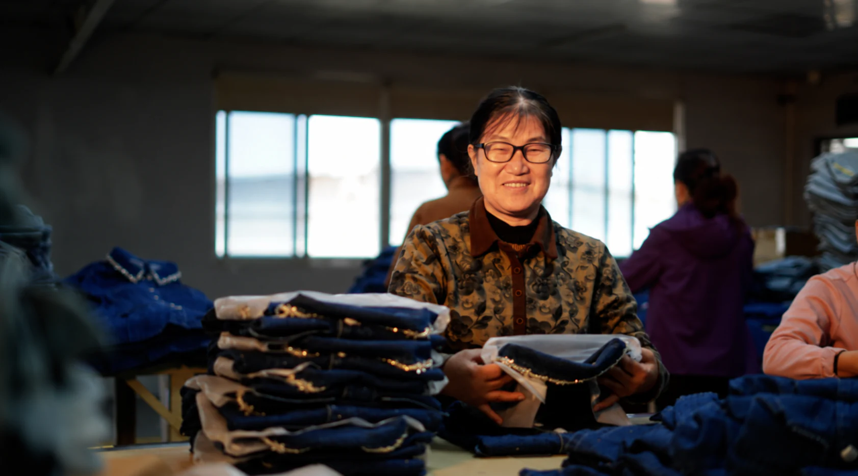 Garment worker sorting finished denim pieces in the workshop