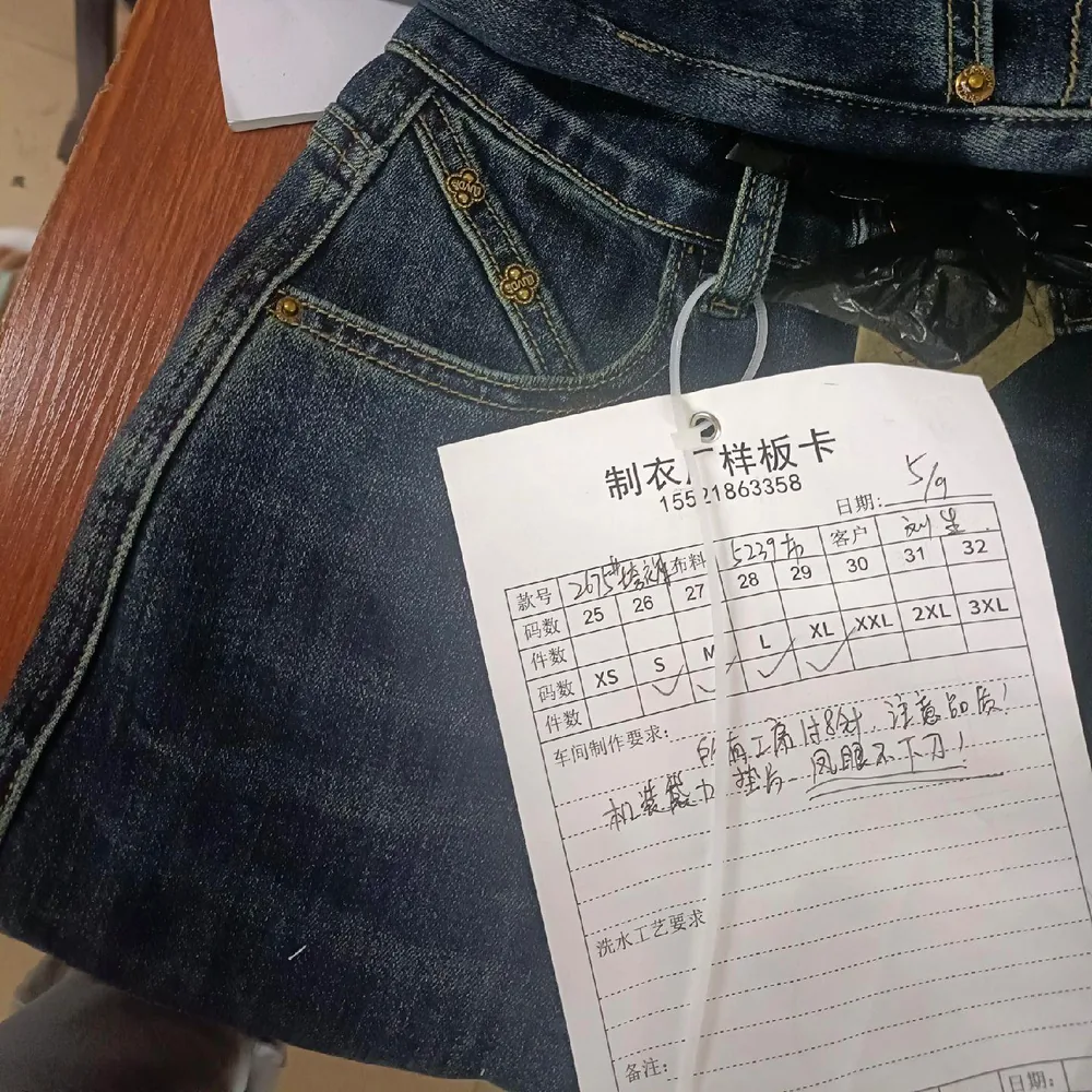 Denim garment sample with an attached production approval card